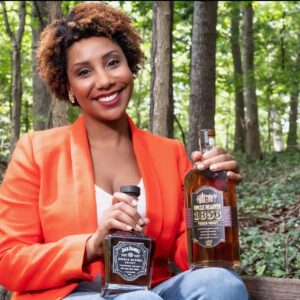 Image of Tracie Franklin holding a bottle of Uncle Nearest Whiskey and a bottle of Jack Daniel's Single Barrel